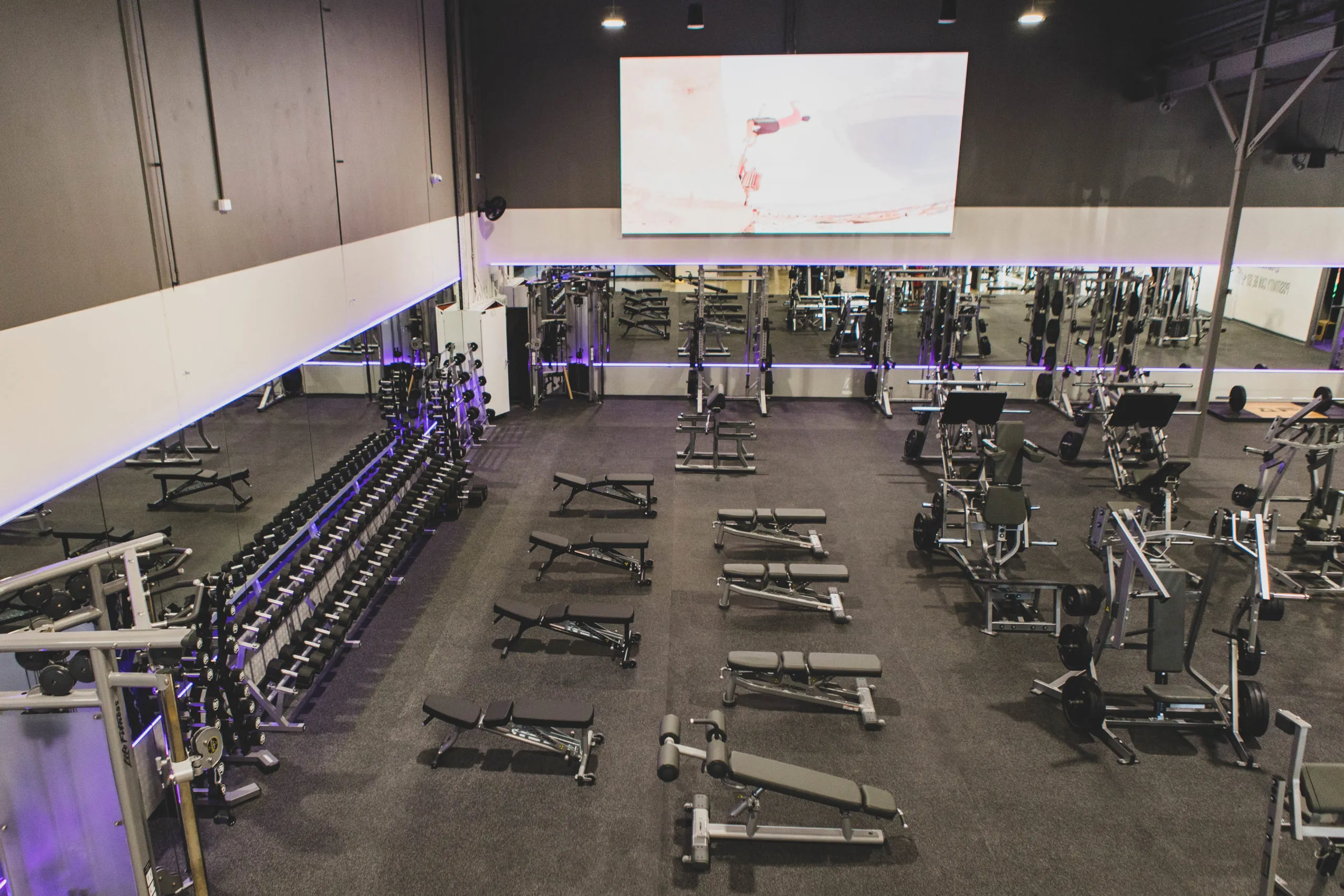 A wall-scale indoor LED screen mounted high above the gym floor at Anytime Fitness, running video across the training area