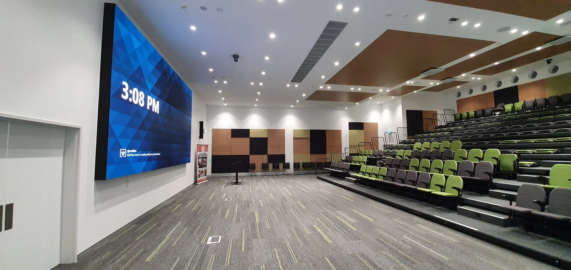 A wide auditorium with a large screen at the front of the room