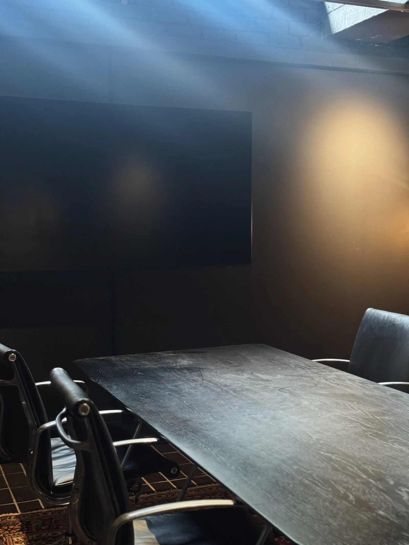 A shaft of daylight falling across the dark meeting room of The Bunker, its display and surfaces disappearing into the architecture