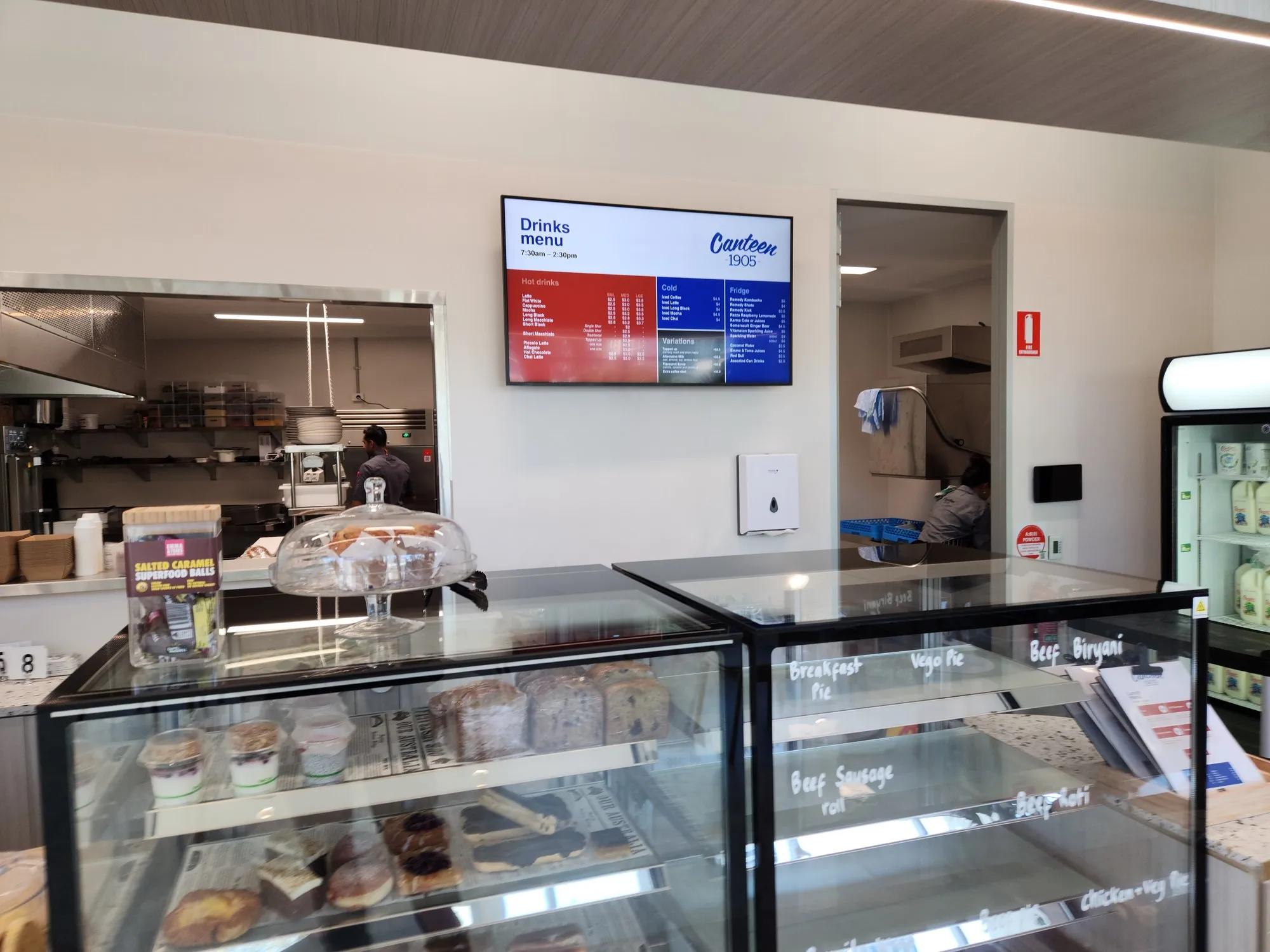 A digital drinks-menu screen mounted above the cafe counter