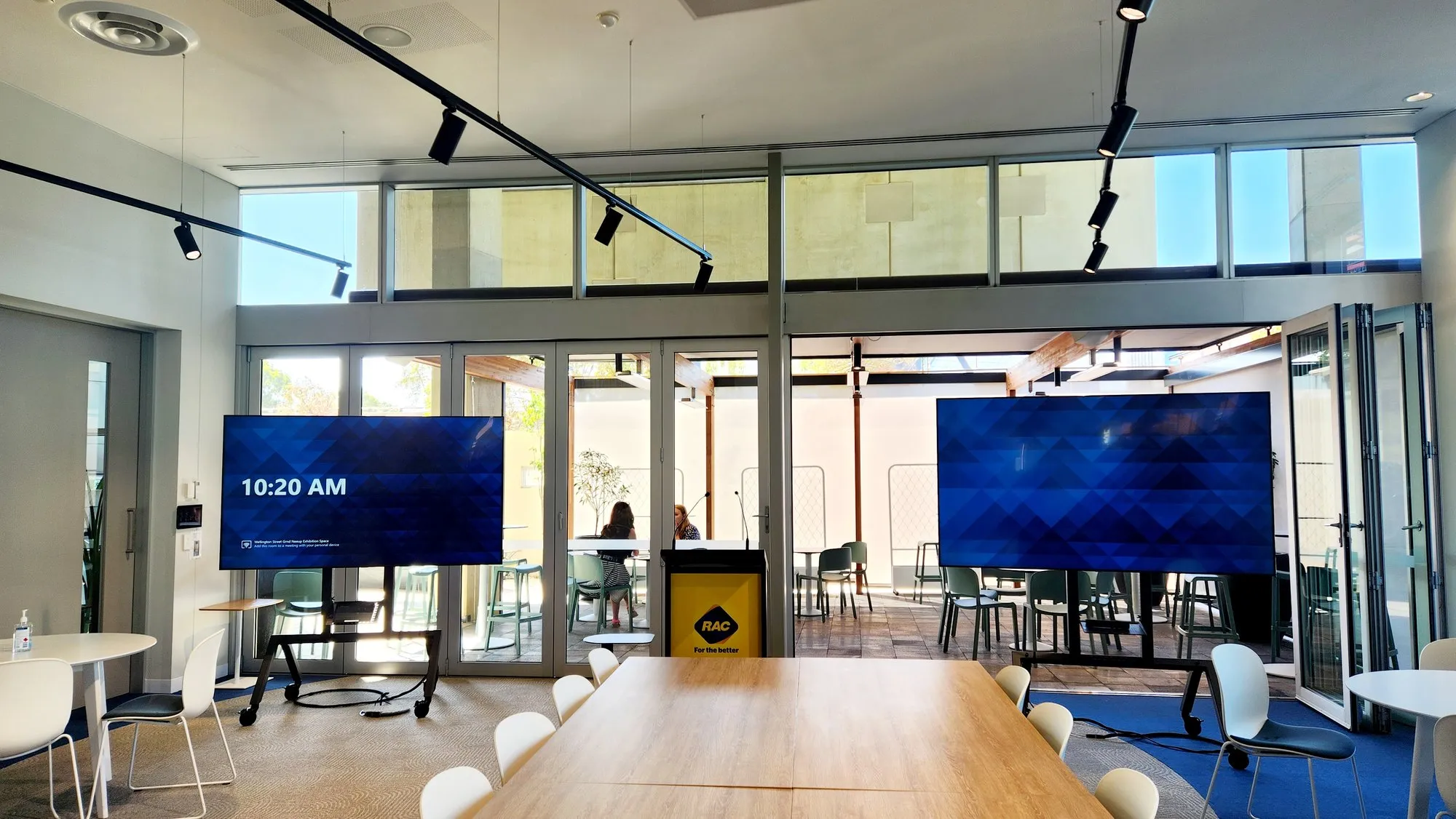 An open collaboration area with dual displays, glazed doors and desks beyond