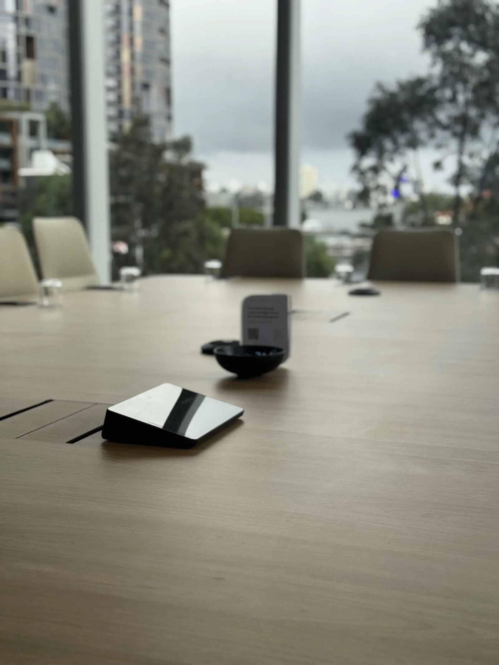 The boardroom table at Hub Australia, Nine The Esplanade — touch controller at hand and the city skyline beyond