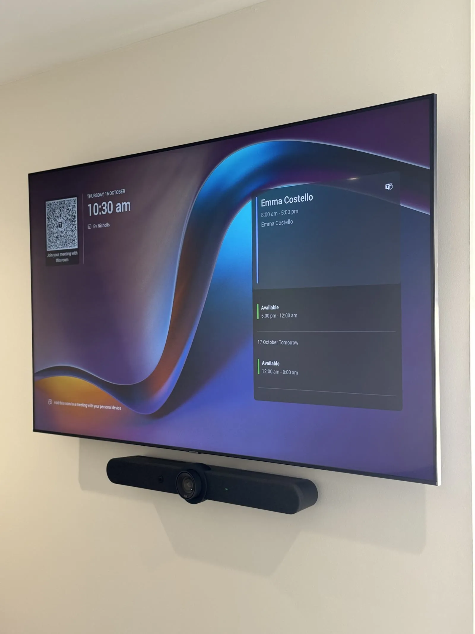 A wall display showing the Microsoft Teams Rooms home screen with the room's calendar and join QR code, a Rally Bar Mini mounted beneath it, at RAAFA WA