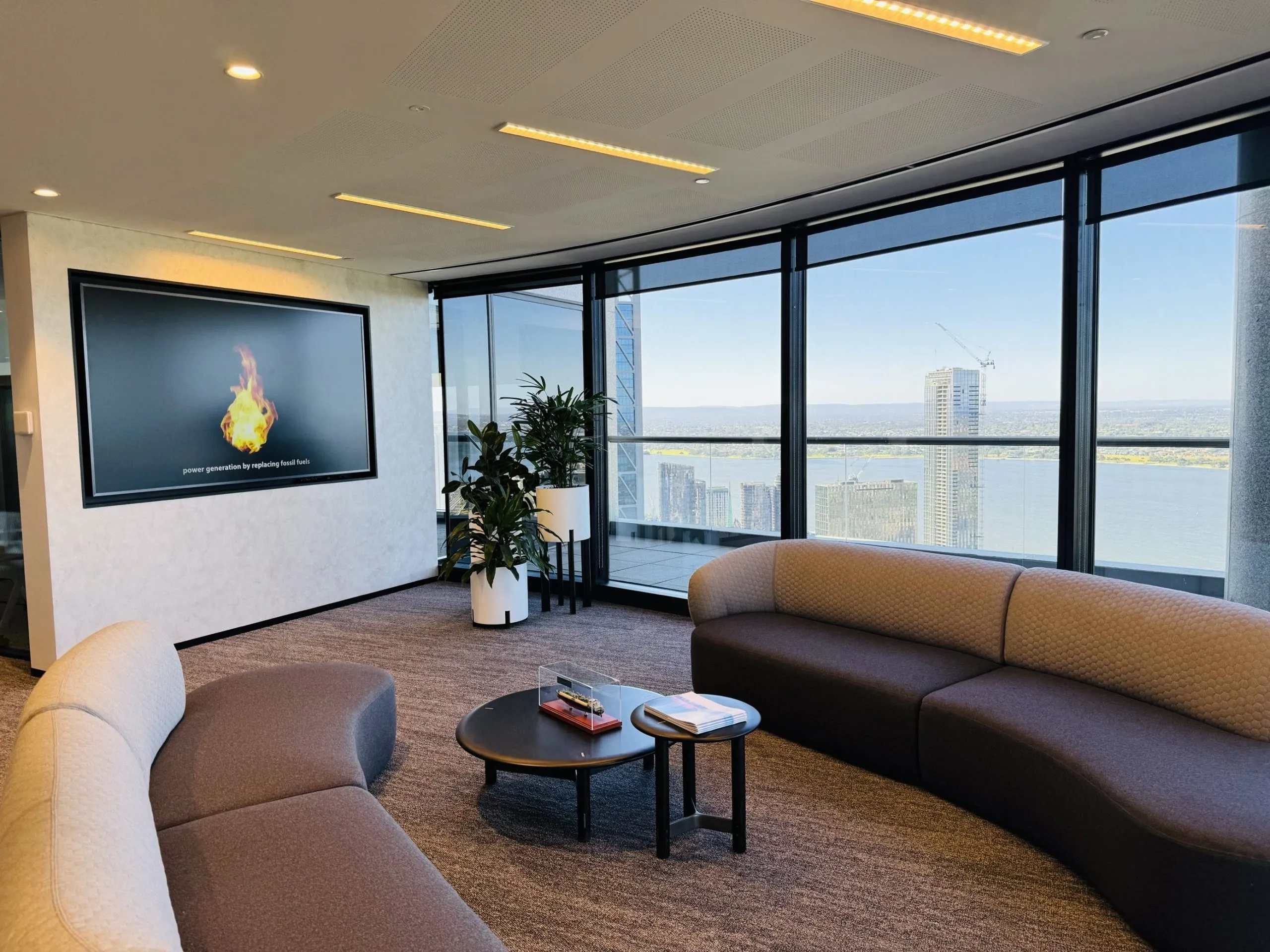 A Perth executive lounge where a perforated acoustic ceiling absorbs reflections around a wall-mounted display
