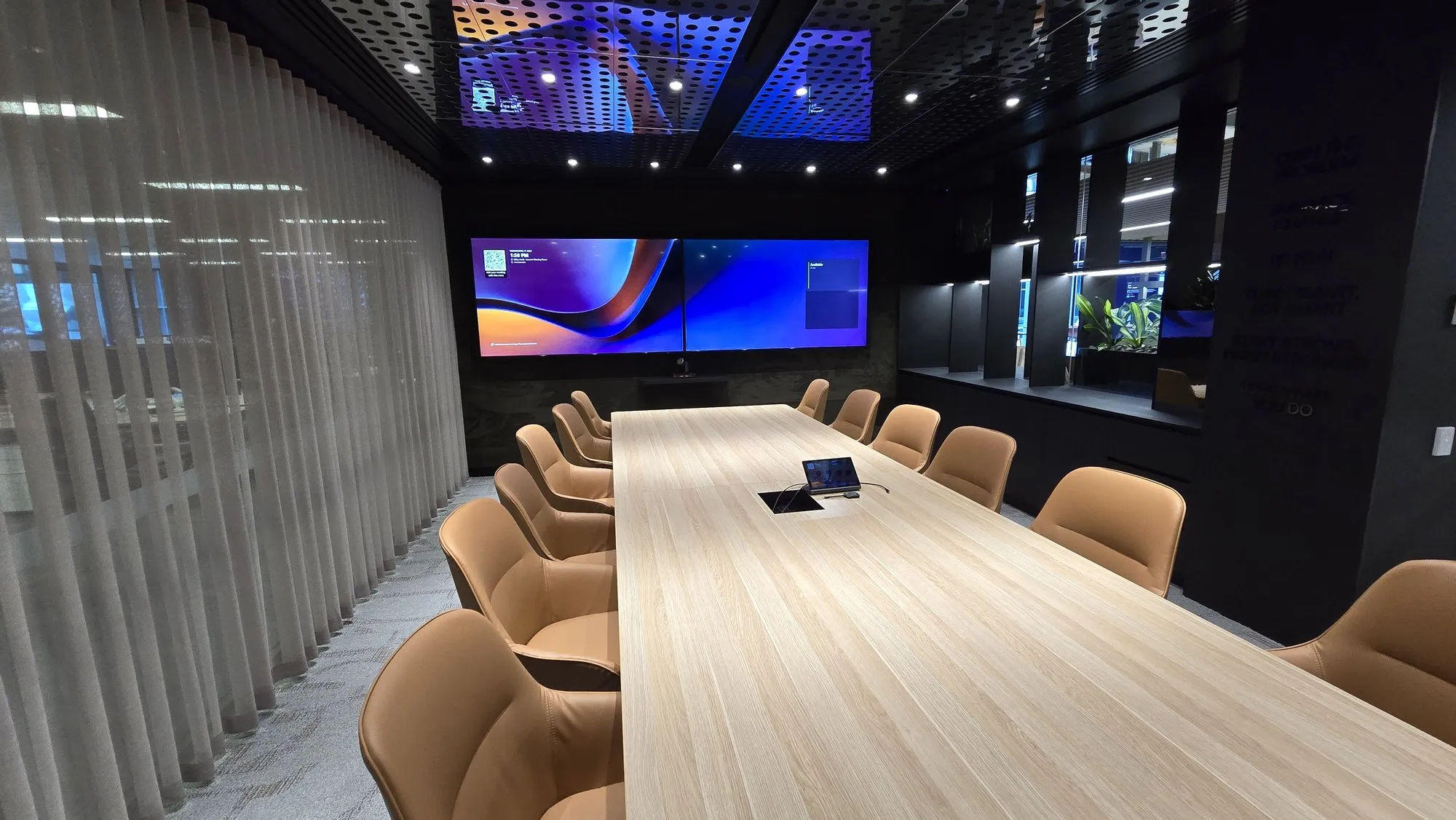 An executive boardroom with a long table and displays at the end wall
