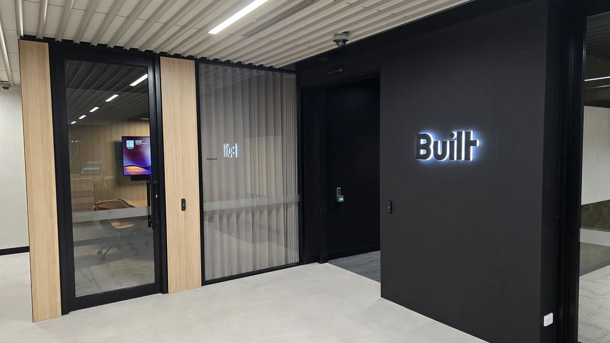 A corridor lined with fluted timber acoustic battens beside glazed meeting rooms