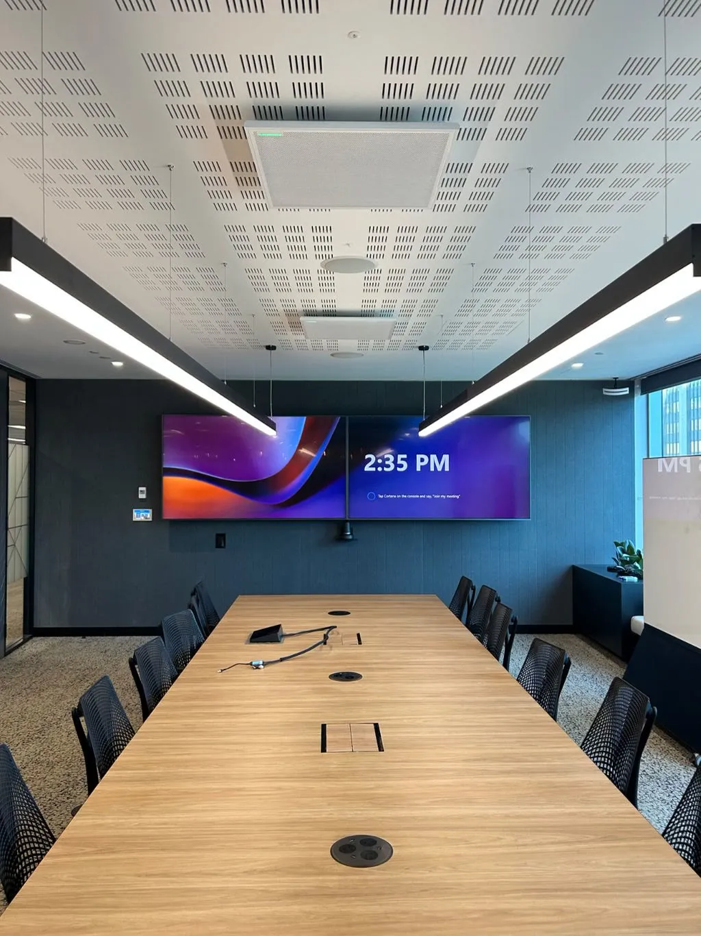 The CBH Group boardroom by Focus AV — dual displays on a dark feature wall, ceiling microphone, acoustic ceiling and integrated cable access in the table