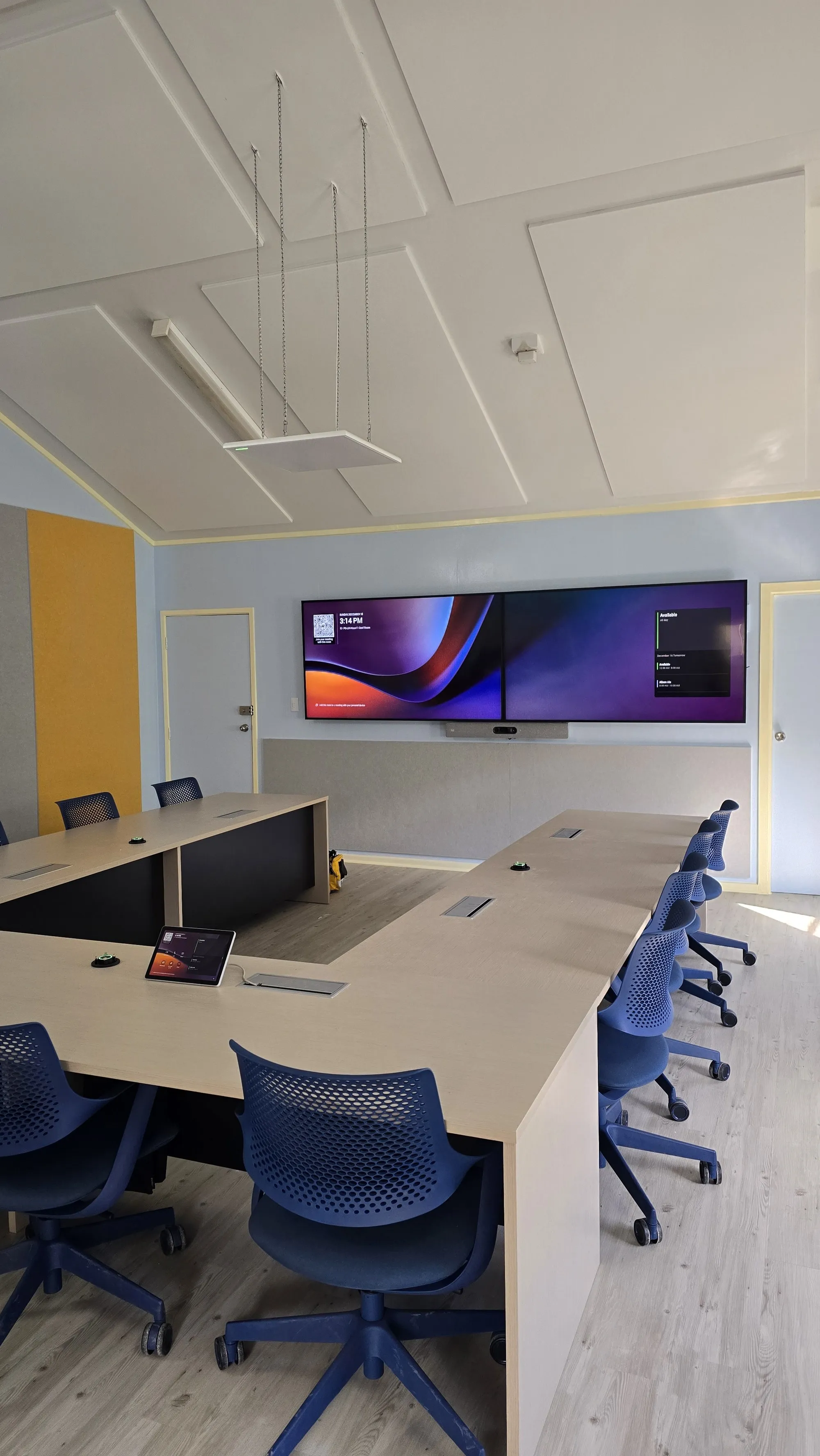 A finished conference room with acoustic ceiling rafts overhead and fabric panels down the walls