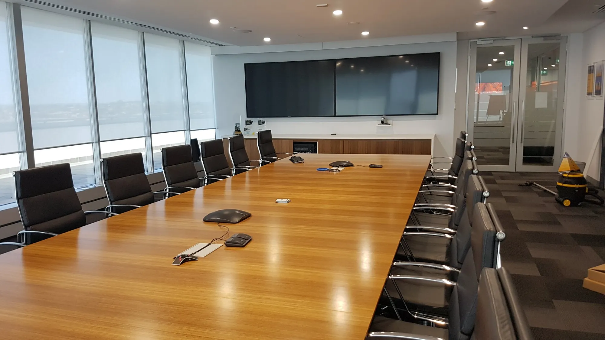 A long timber boardroom table with chairs, glazing along one wall