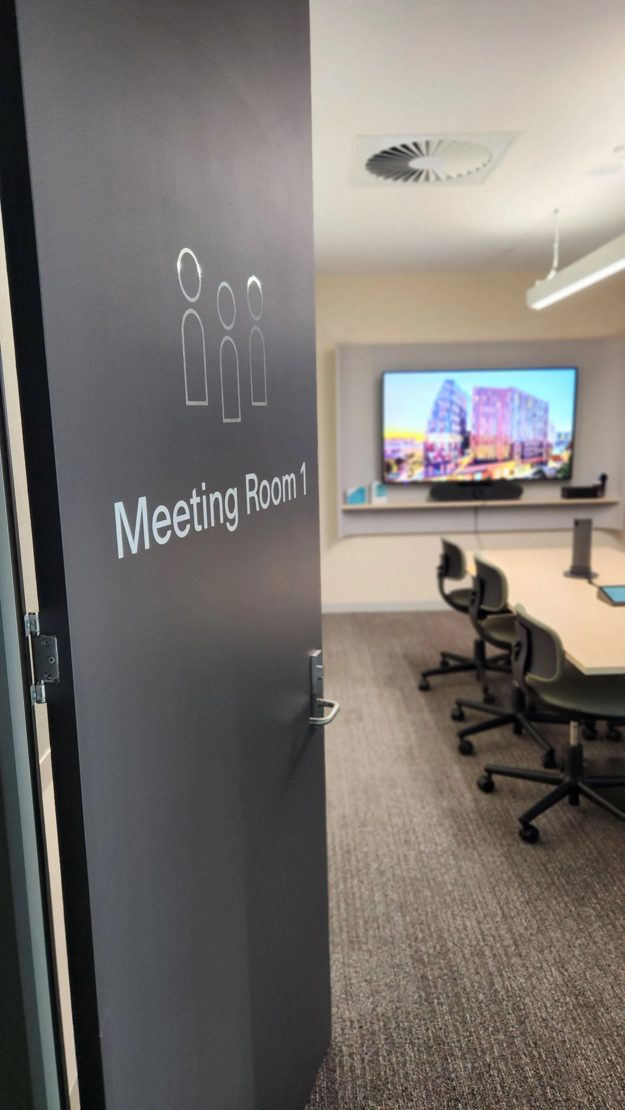 A meeting room seen past its signed door with the display lit inside