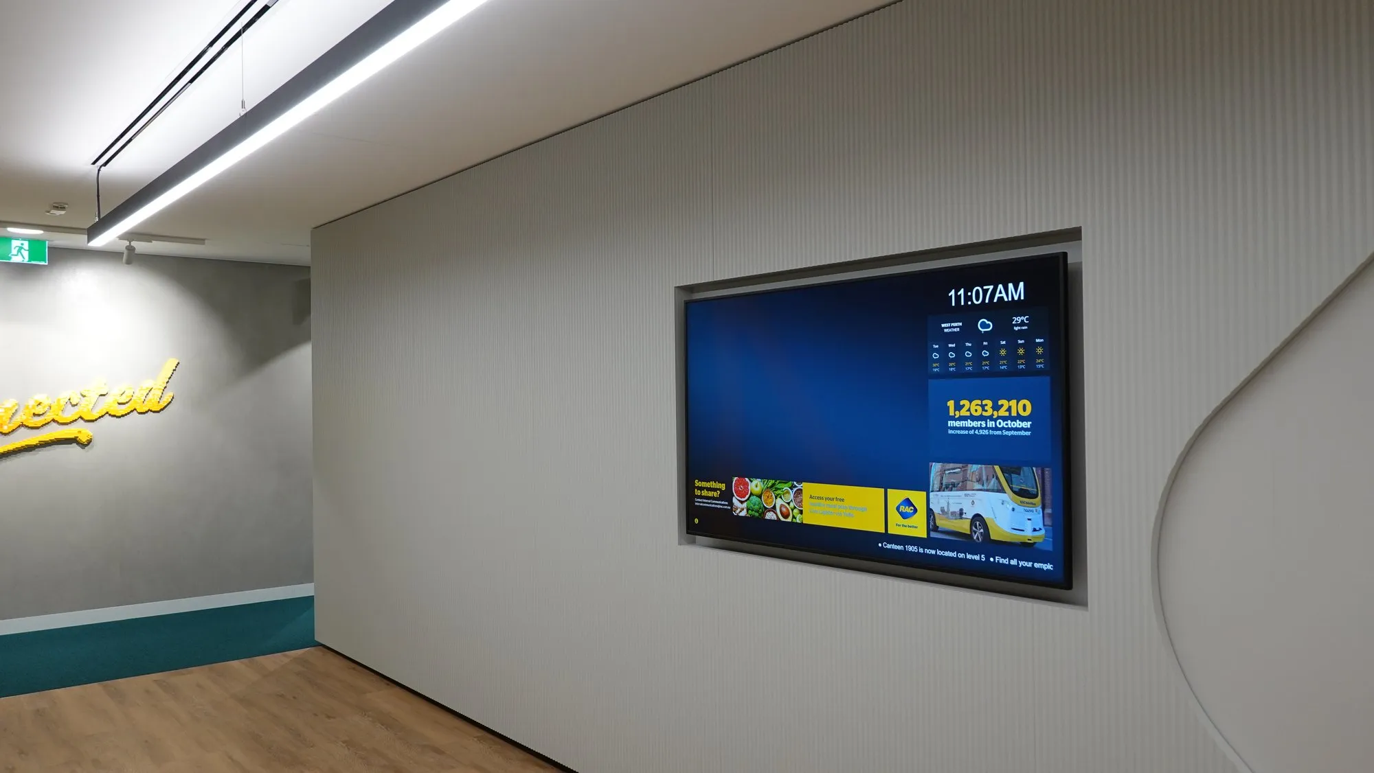 A wall display in an office corridor running an internal campaign with a live counter and transit times