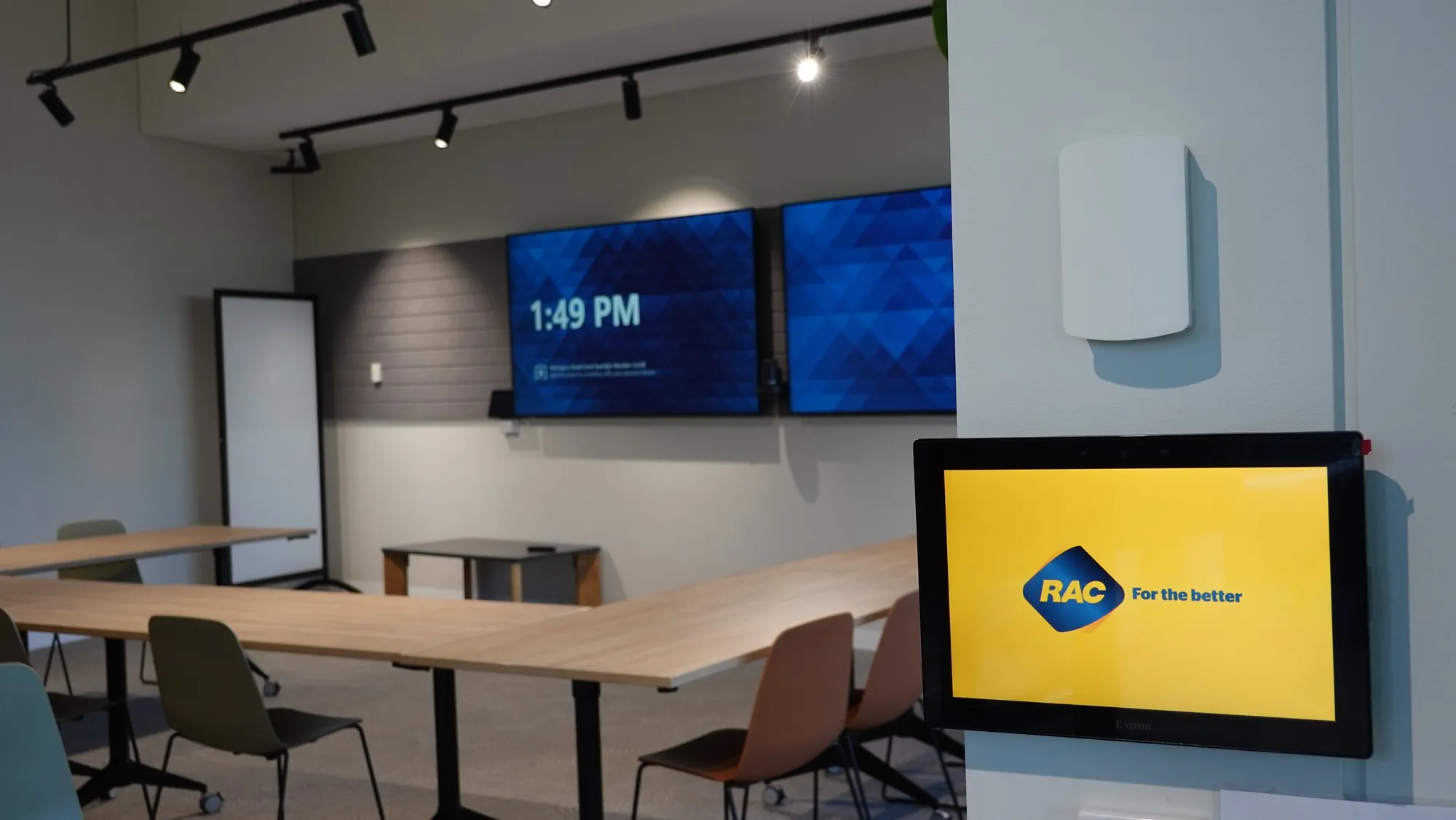 A four-panel video wall carrying brand content in an RAC workplace meeting space