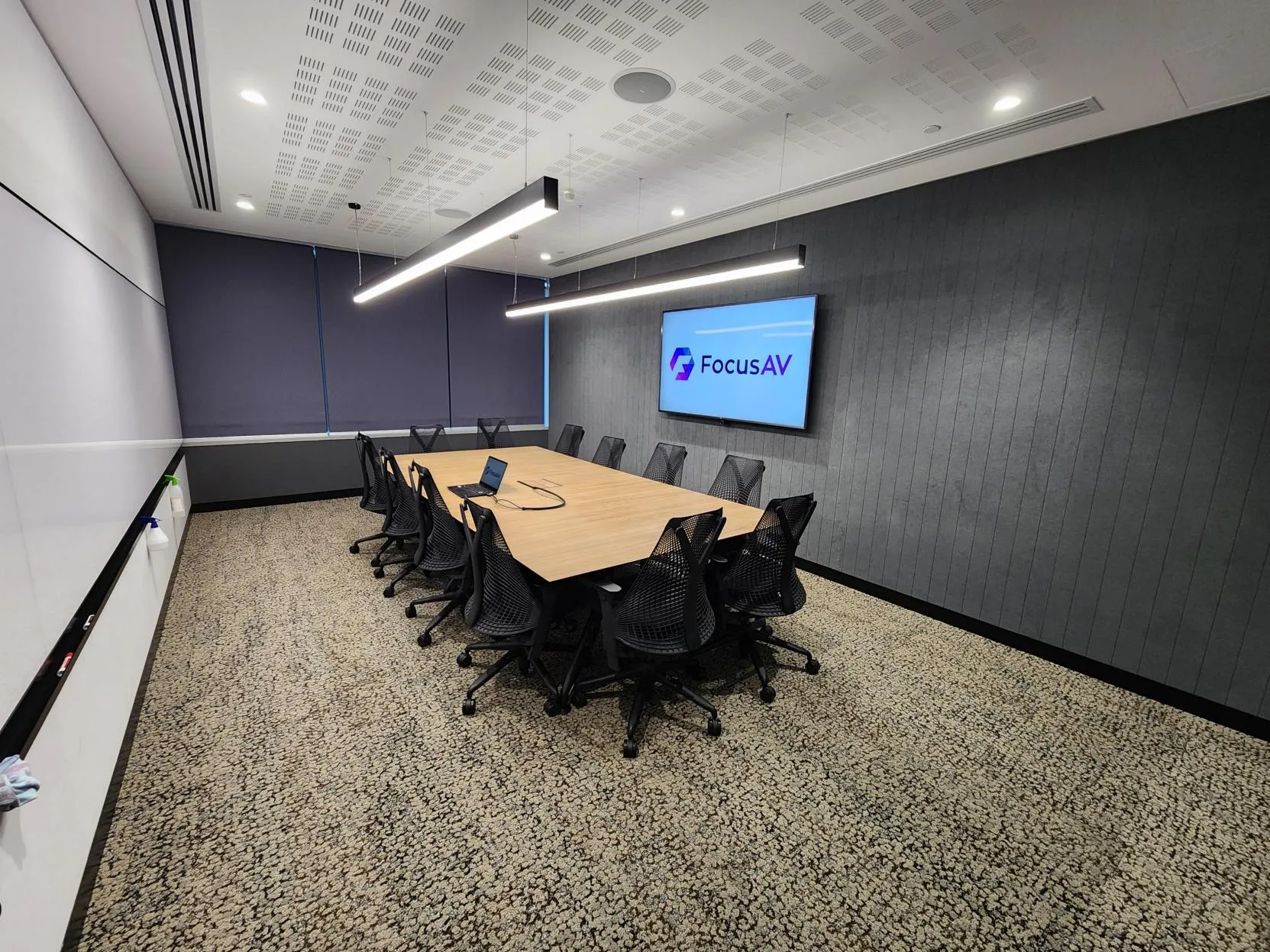 A boardroom with fabric-wrapped acoustic panels running the length of the wall beside the display