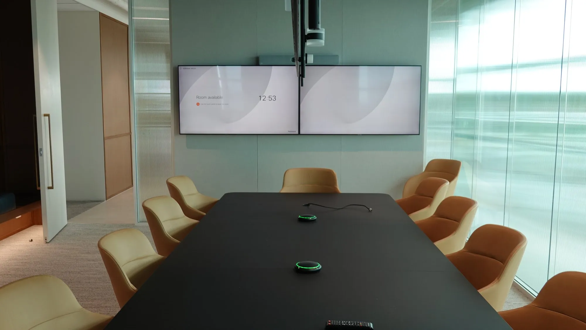 The Newmont boardroom in Perth — long dark table, cognac leather chairs, dual displays and a PTZ camera on the end wall