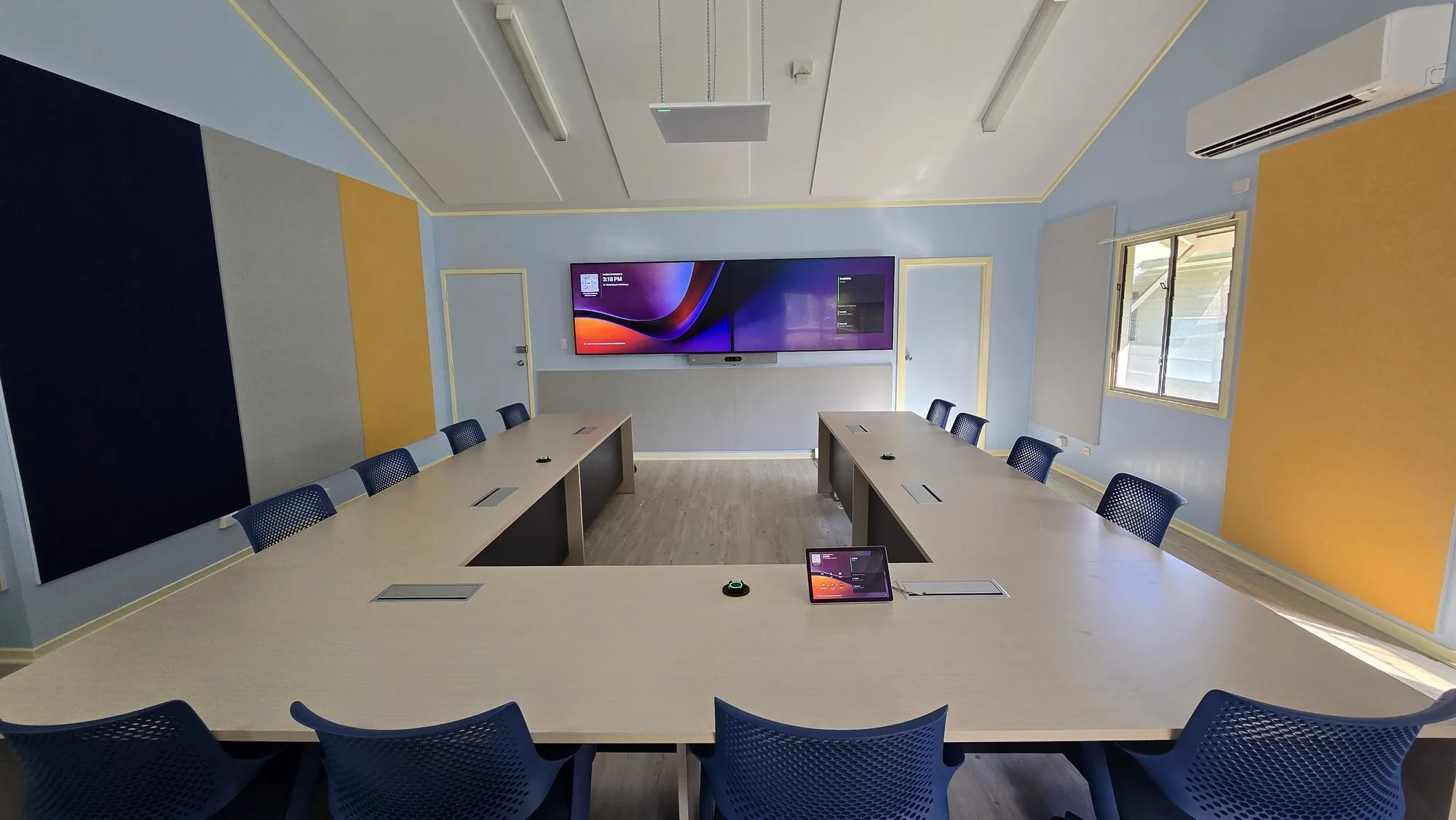 A large Focus AV training and town-hall room with a wide display on a video call
