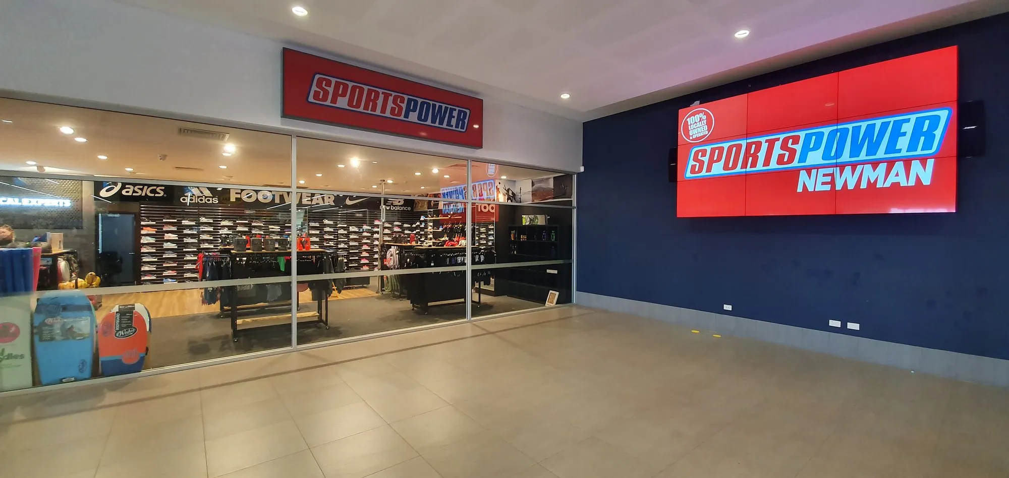 A large commercial display at a retail storefront, running brand content beside the shopfront glass