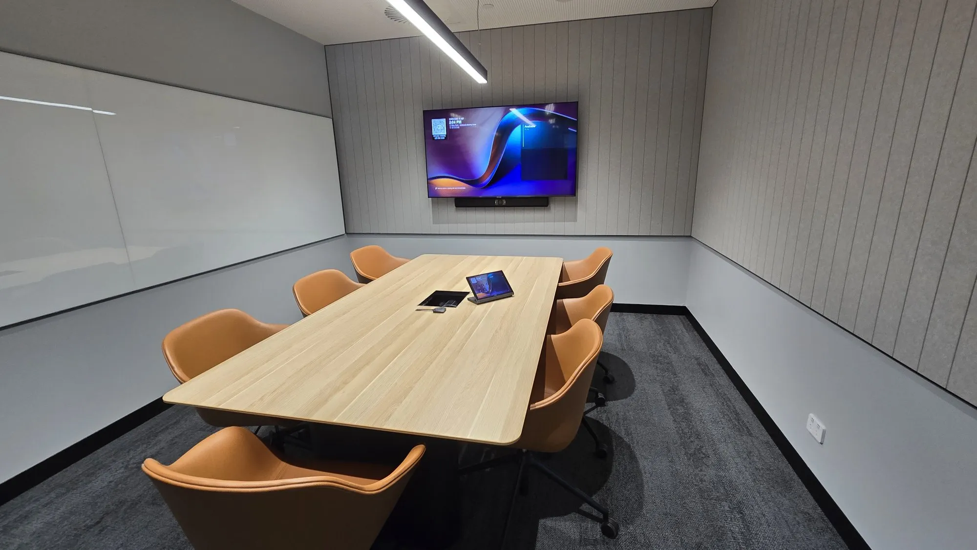 A meeting room with ribbed acoustic wall panels behind a wall-mounted display