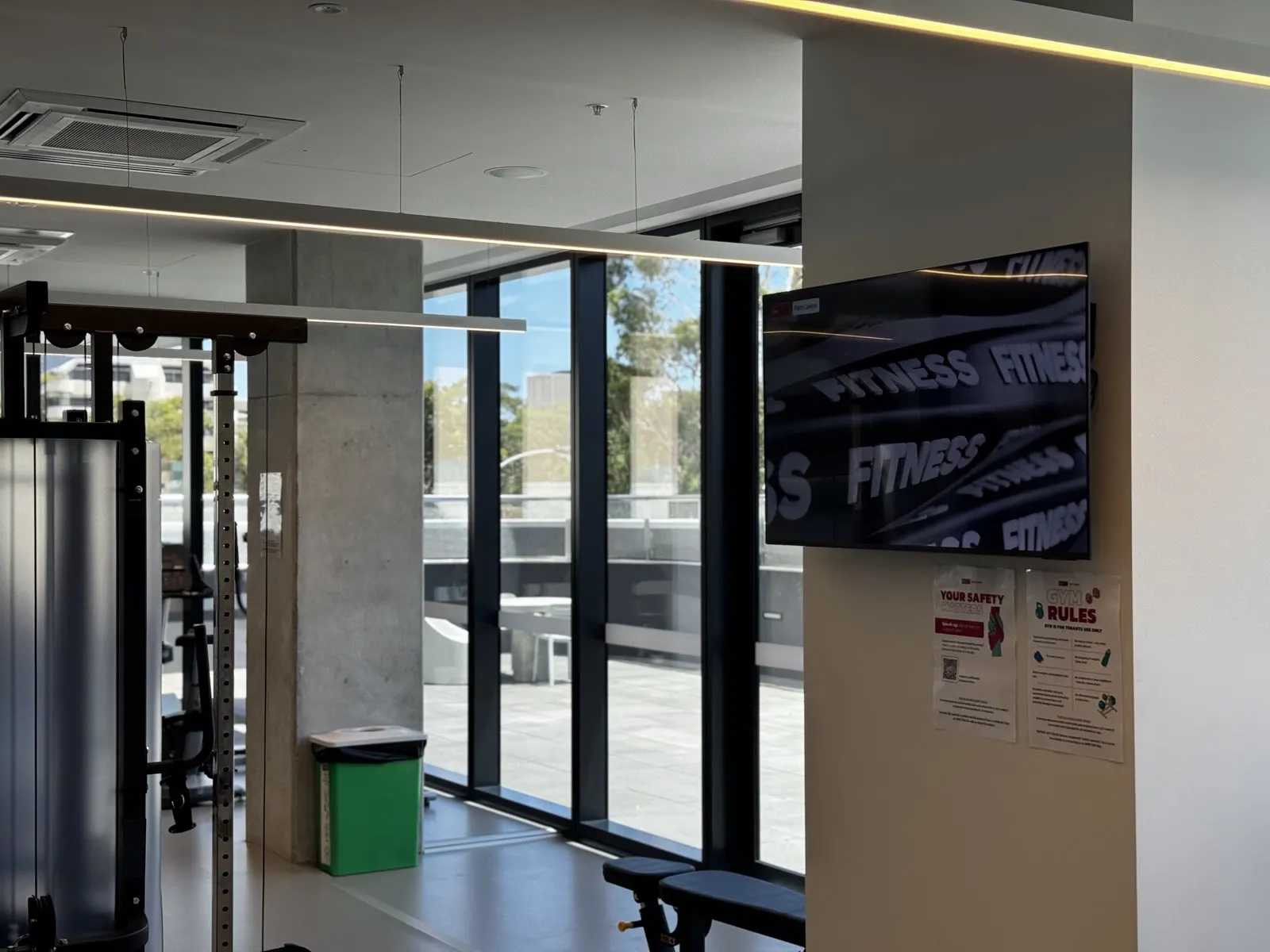 A tenant gym screen running an in-house fitness channel on the building's signage network