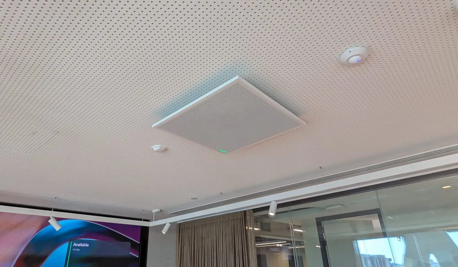 A ceiling microphone tile sitting flush in the perforated acoustic ceiling of a Newmont meeting room