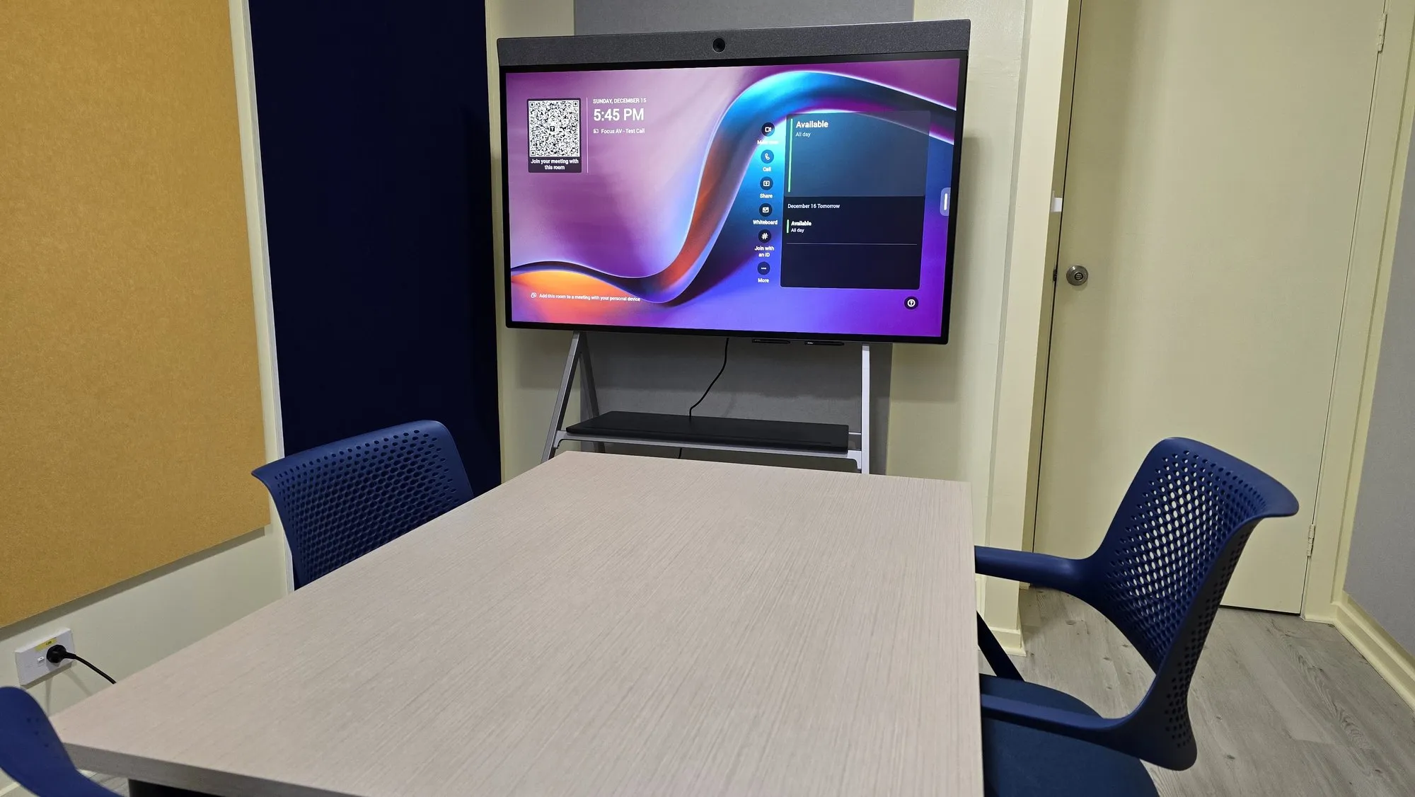 A small room with a display on a mobile stand between acoustic wall panels