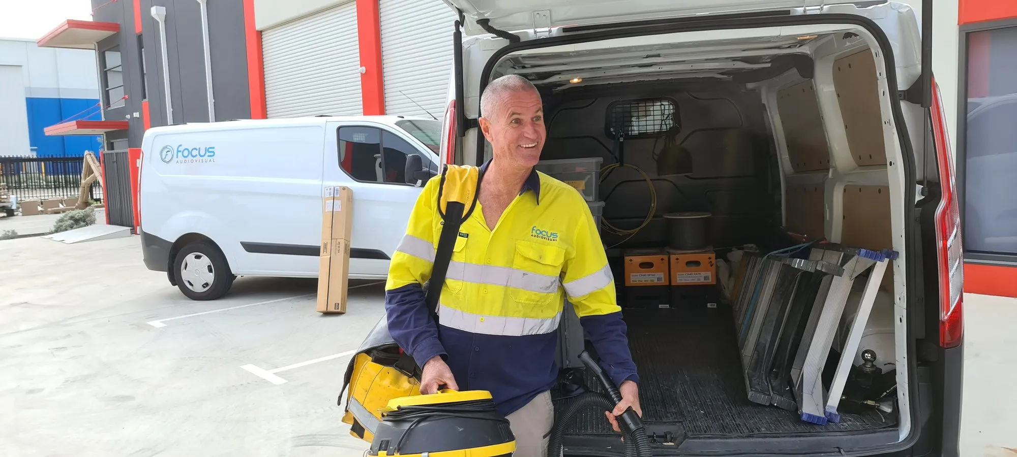 A Focus AV technician loading service kit into the branded van