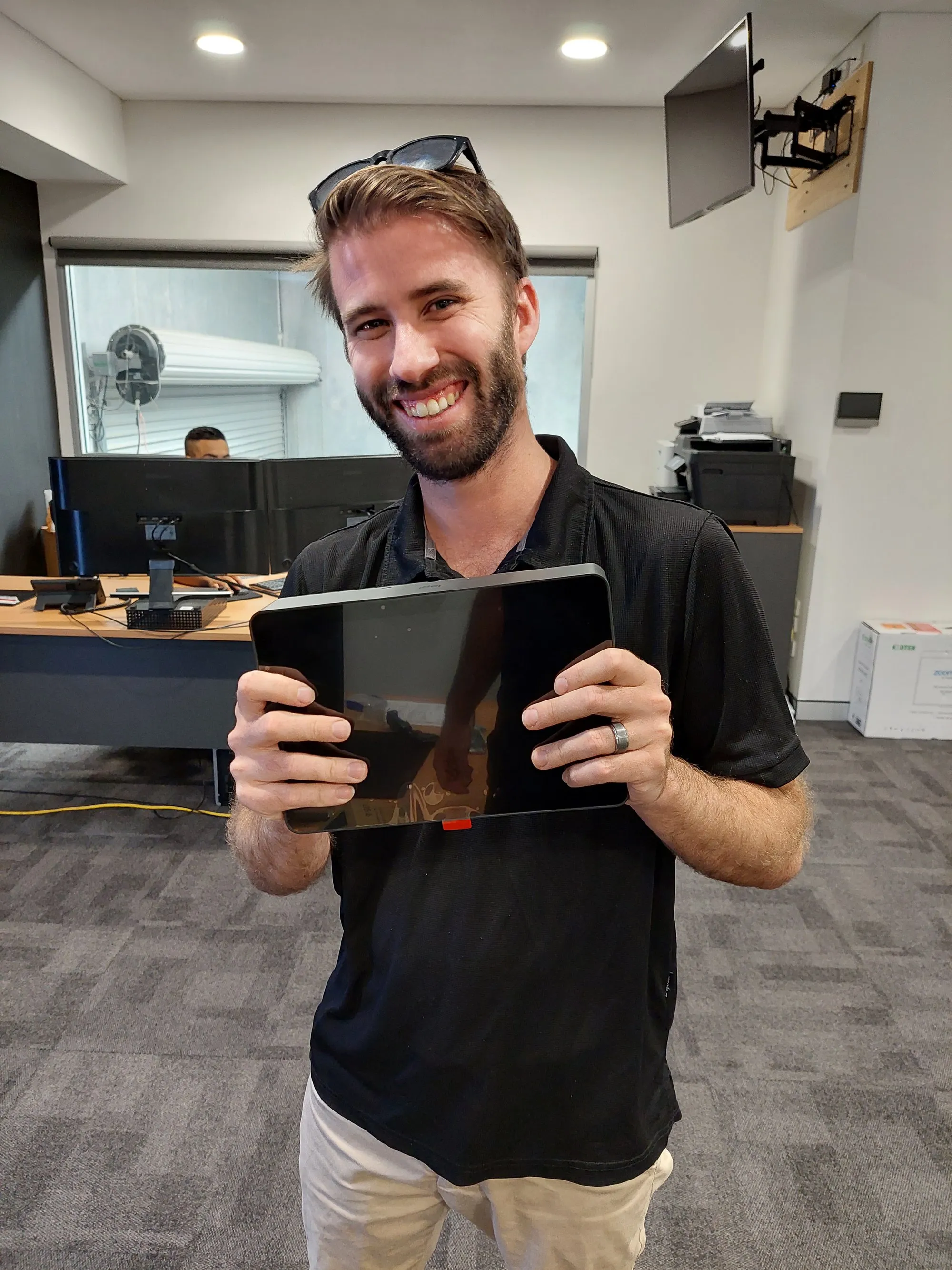 A smiling Focus AV technician holding a touch controller in a meeting room mid-fit-out