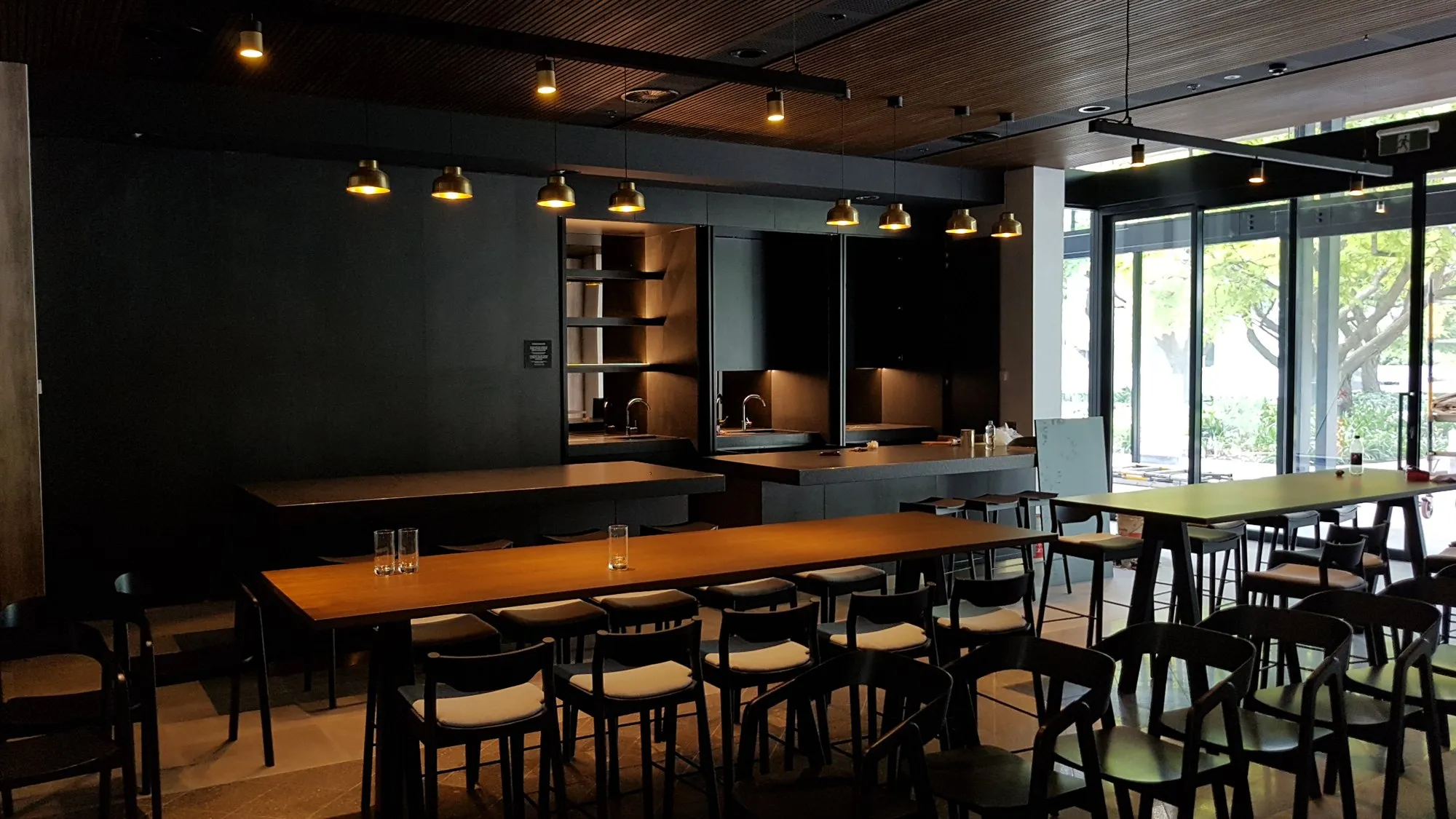 A venue interior with timber tables, stools and a bar
